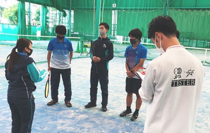 GODAIスポーツアカデミーのテニスコートで講師の指導を受ける学生たち