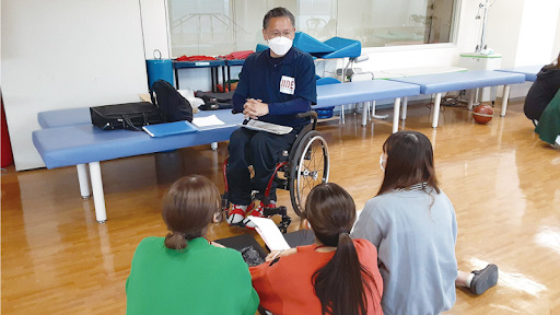 車いすの人の話を聞く３人の女性