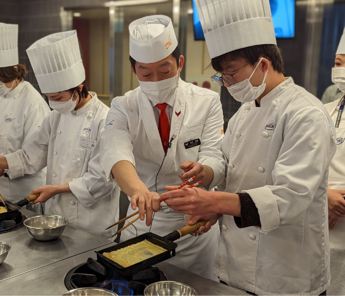 卵焼きを指導される男性