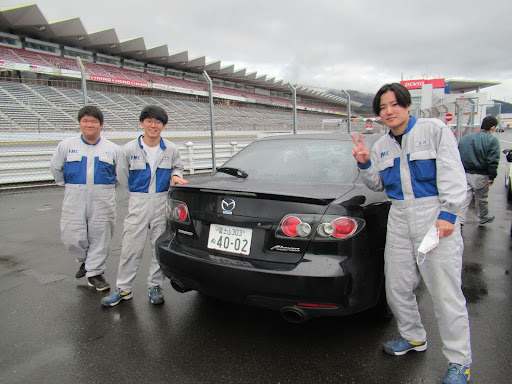 車の後ろ部分で写真を撮る3人の男性